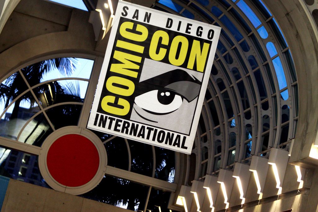 a comic con international sign is hanging from the ceiling of a building .