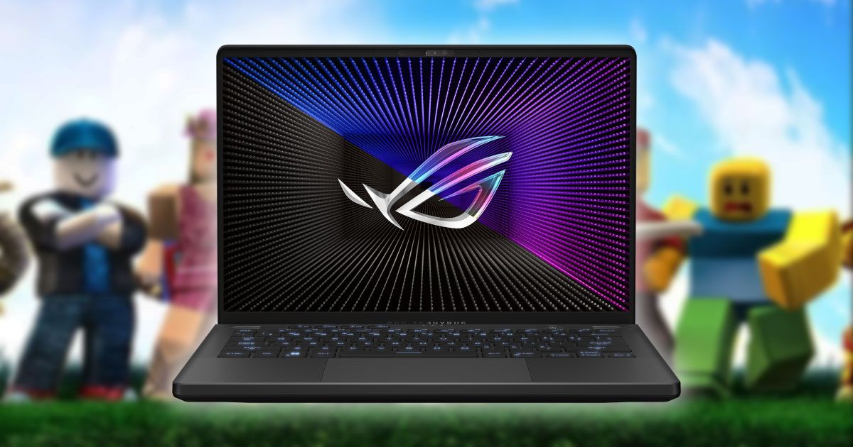 A black laptop with grey, blue, and purple branding on the display. The laptop is in front of a blurry image from Roblox.