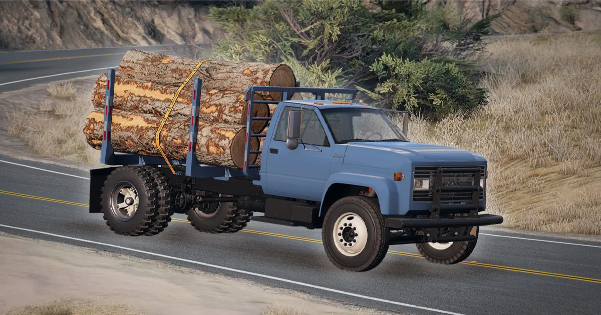 A blue truck with logs strapped to its back.