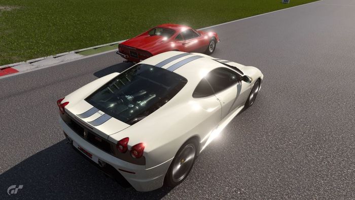 a white sports car is driving next to a red sports car on a race track .