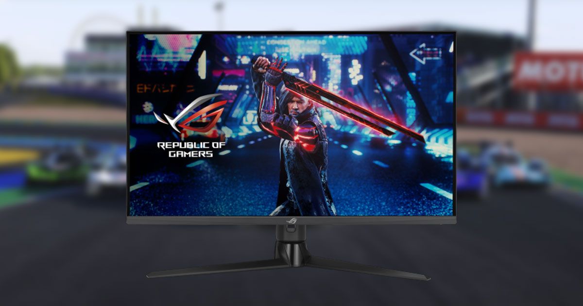 A black near-frameless monitor with a video game character holding a red glowing sword on the display in front of a blurry image of cars lined up on a track in the background.