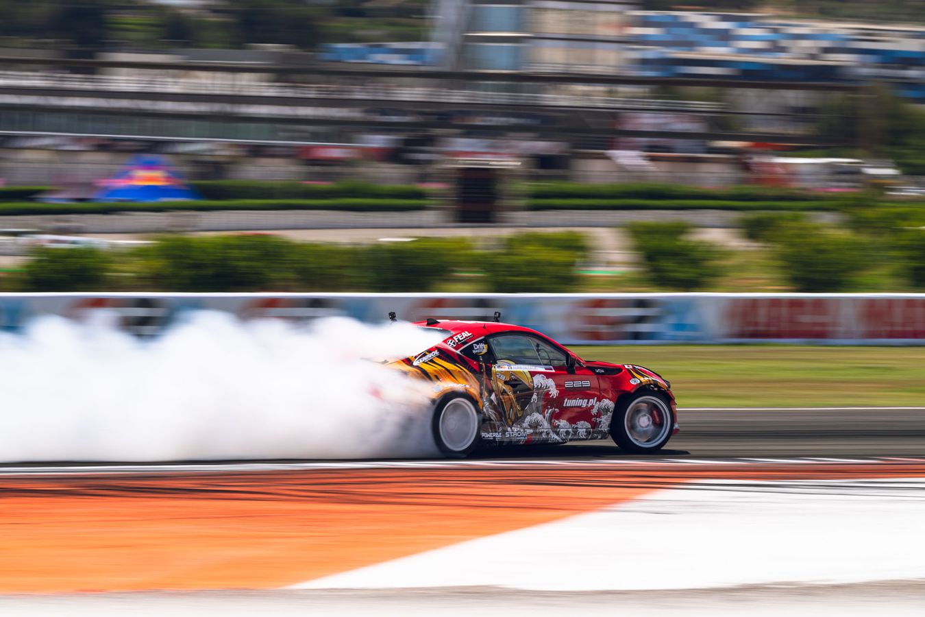 A red racing car is drifting on a race track in the Drift Masters championship.