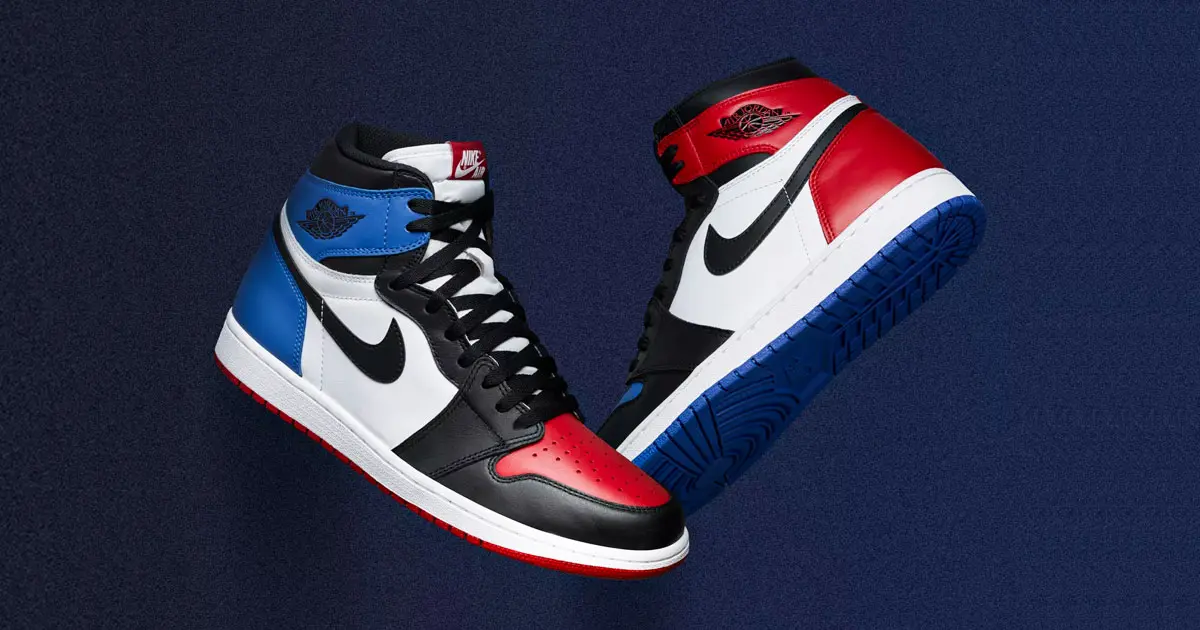 A pair of white, black, red, and blue Jordan 1 Highs in front of a blue background.