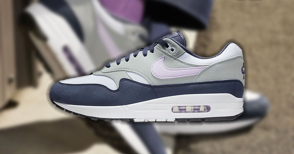 A white, gray, and navy Air Max 1 featuring a light pink Swoosh down the side.