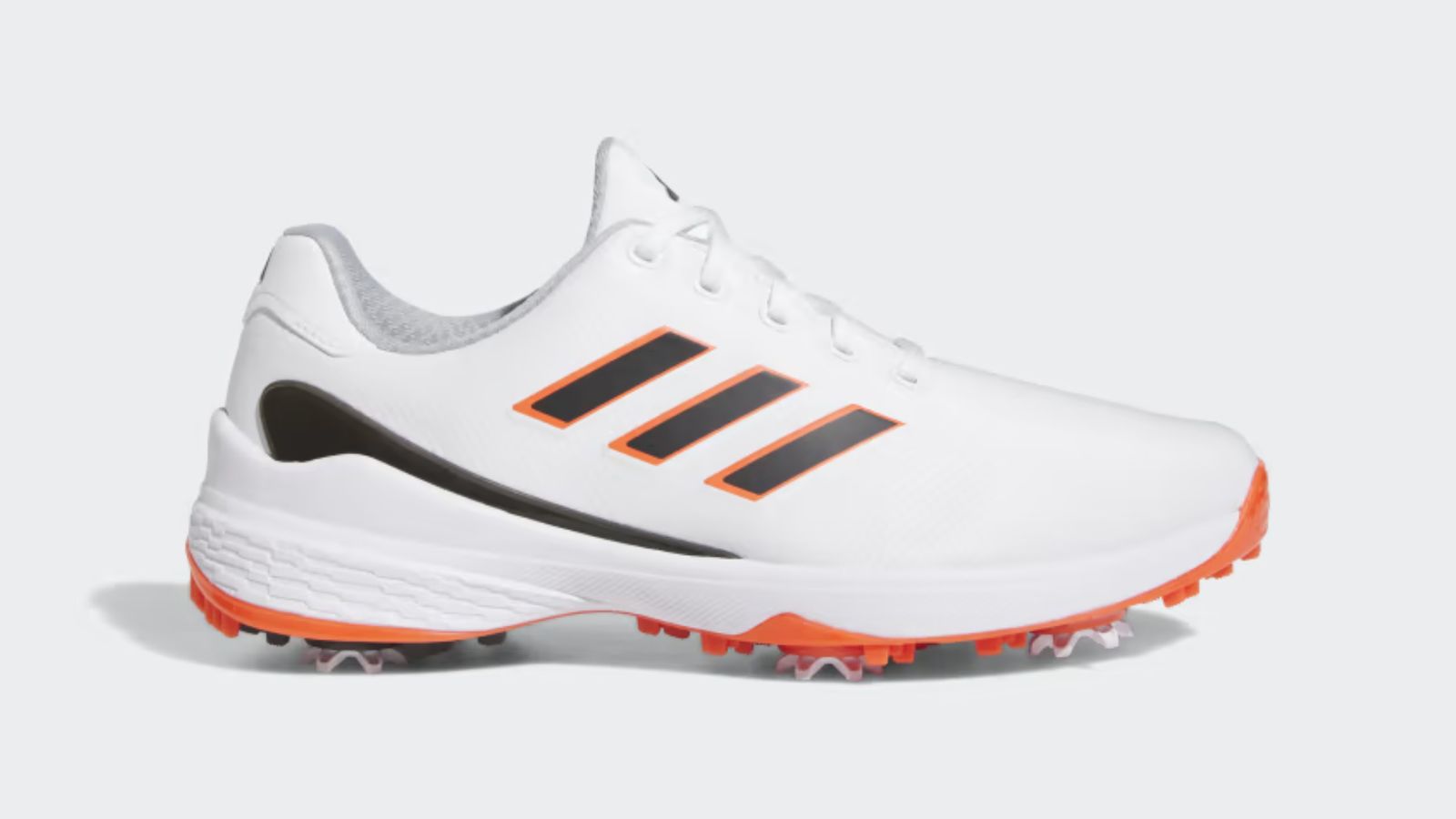 adidas ZG23 product image of a white golf shoe with black stripes down the side with orange trim to match the sole plate.