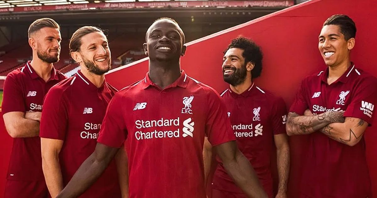 Image of a group of Liverpool players wearing red collared football shirts.