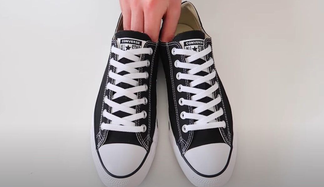 Image of black Converse sneakers with white laces done up to the top.