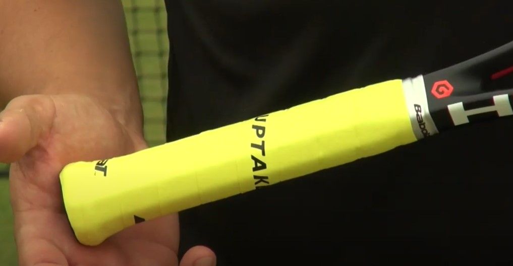 Bright yellow grip tape wrapped around a tennis racquet handle.