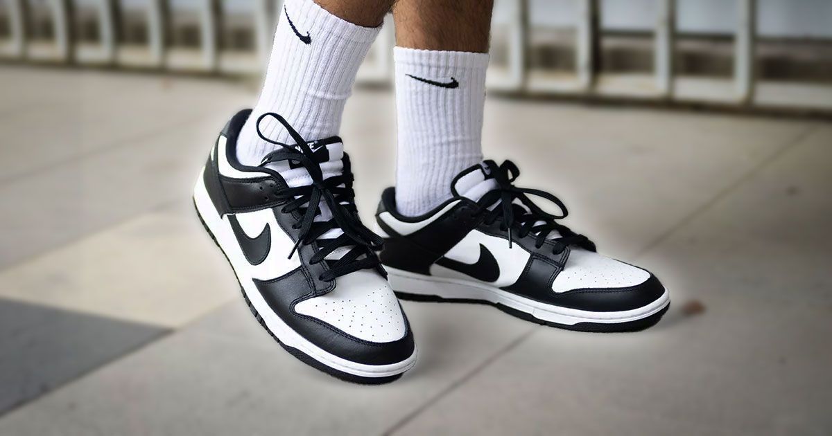 a person is wearing a pair of black and white nike dunk low sneakers .