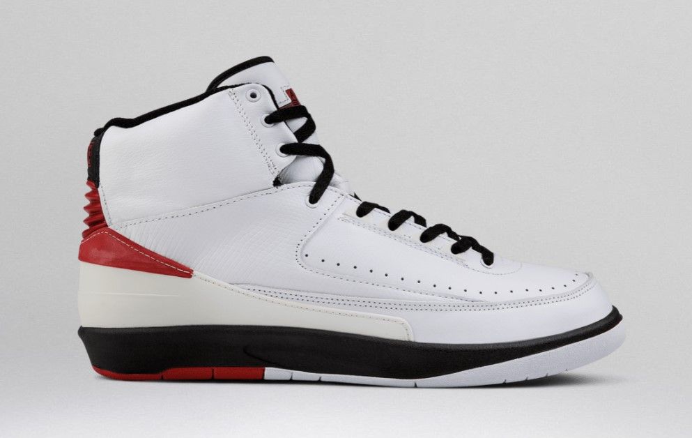 Air Jordan 2 "Chicago" product image of a pair of white, black, and red sneakers on a red background.