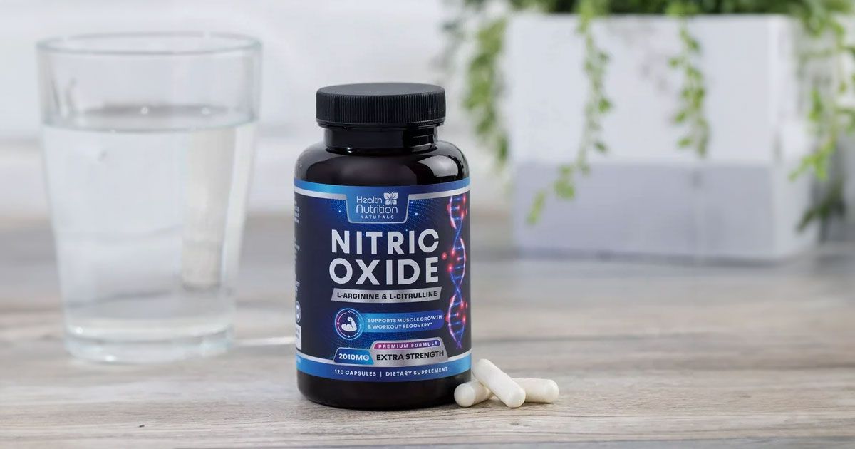 A black container with blue labelling and silver branding next to a glass of water.