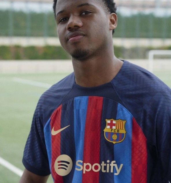 Barcelona home kit 2022/23 product image of a dark blue shirt with red and lighter blue stripes.