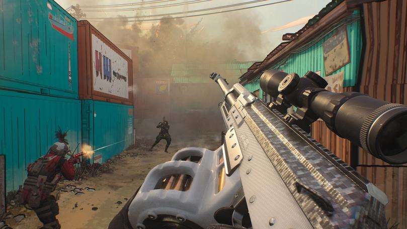 MW3 player holding an Aftermarket Part wile players shoot at each other nearby. The aftermarket part features a drum magazine and a sniper scope