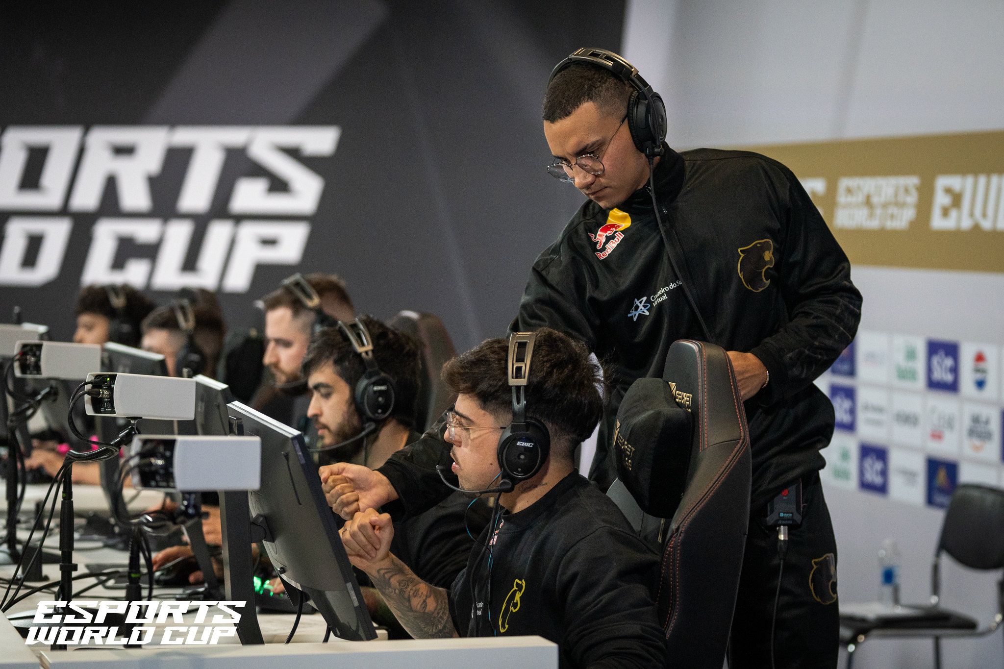 a group of men are sitting in front of computer monitors wearing headphones .