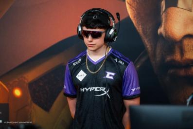 a young man wearing headphones and sunglasses is standing in front of a computer monitor .