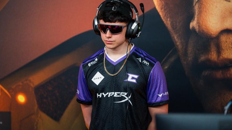 a young man wearing headphones and sunglasses is standing in front of a computer monitor .