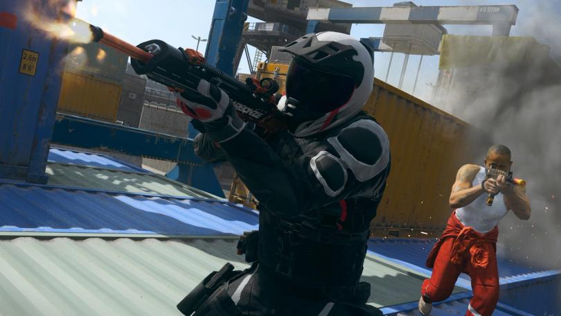 MW3 players firing guns while standing on top of shipping containers. One player is wearing a motorcycle helmet and another is wearing a white vest