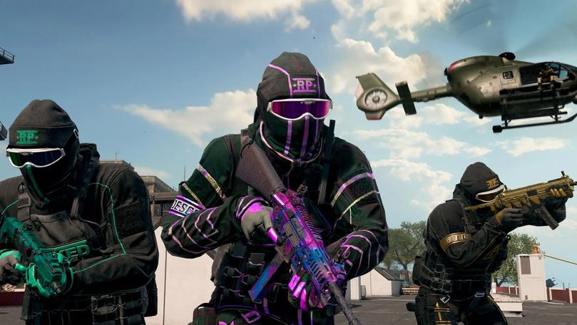 a group of soldiers are standing next to each other in a video game with a helicopter in the background .