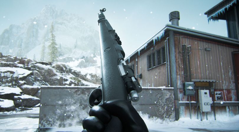 Warzone player holding a Kar98k marksman rifle with snow on rocks and a building in the background