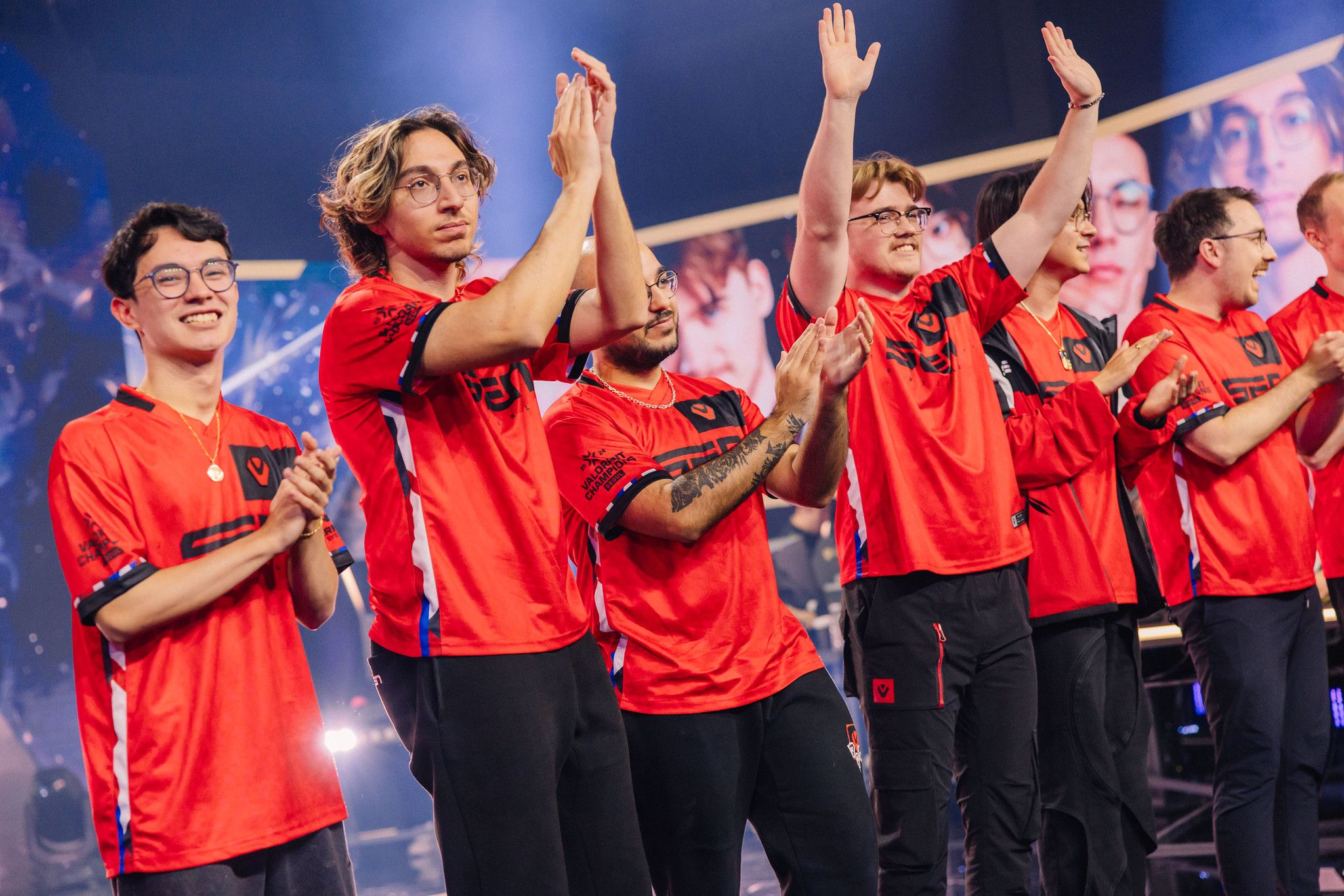 a group of men in red jerseys are standing next to each other on a stage .