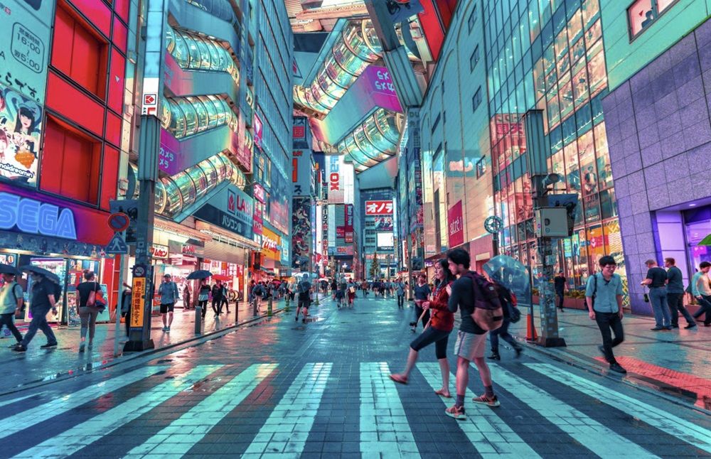 a group of people are crossing a busy street in a city at night .