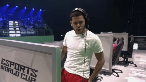 a man wearing headphones stands in front of a sign that says esports world cup