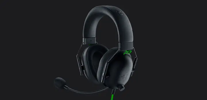 Product image of Razer BlackShark V2 X, a black over-ear headset with a microphone and a green cable.