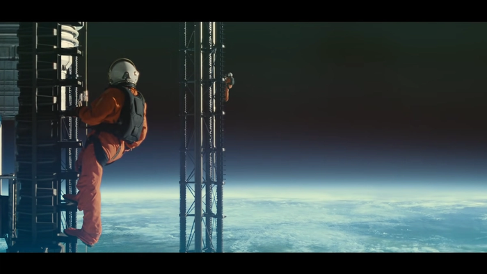 astronauts climb the tall frames of the station