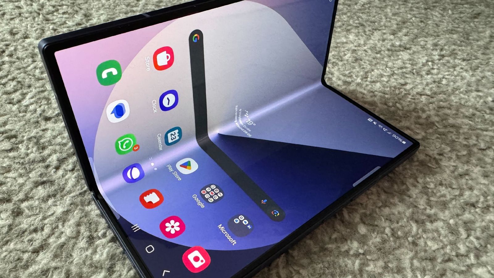 Samsung Galaxy Z Fold 6 in on a grey carpet mid-fold into the larger screen