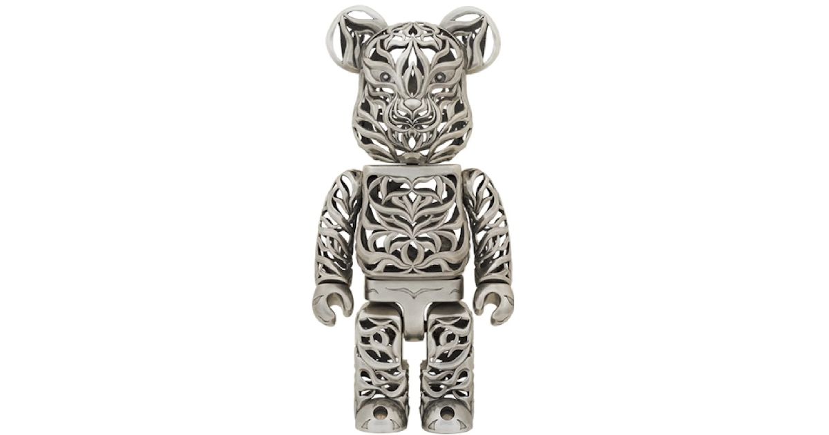 A silver Bearbrick with a cutout pattern all over and a tiger-like face.